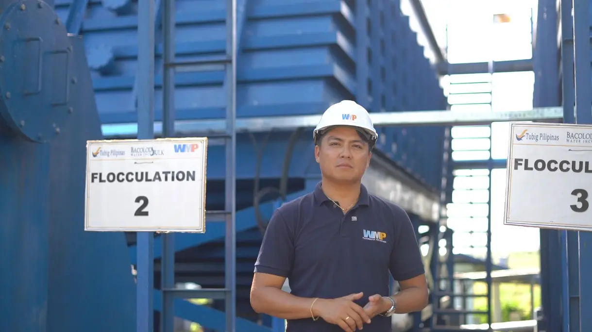 Worker standing in front of the camera with water treatment equipment in the background.