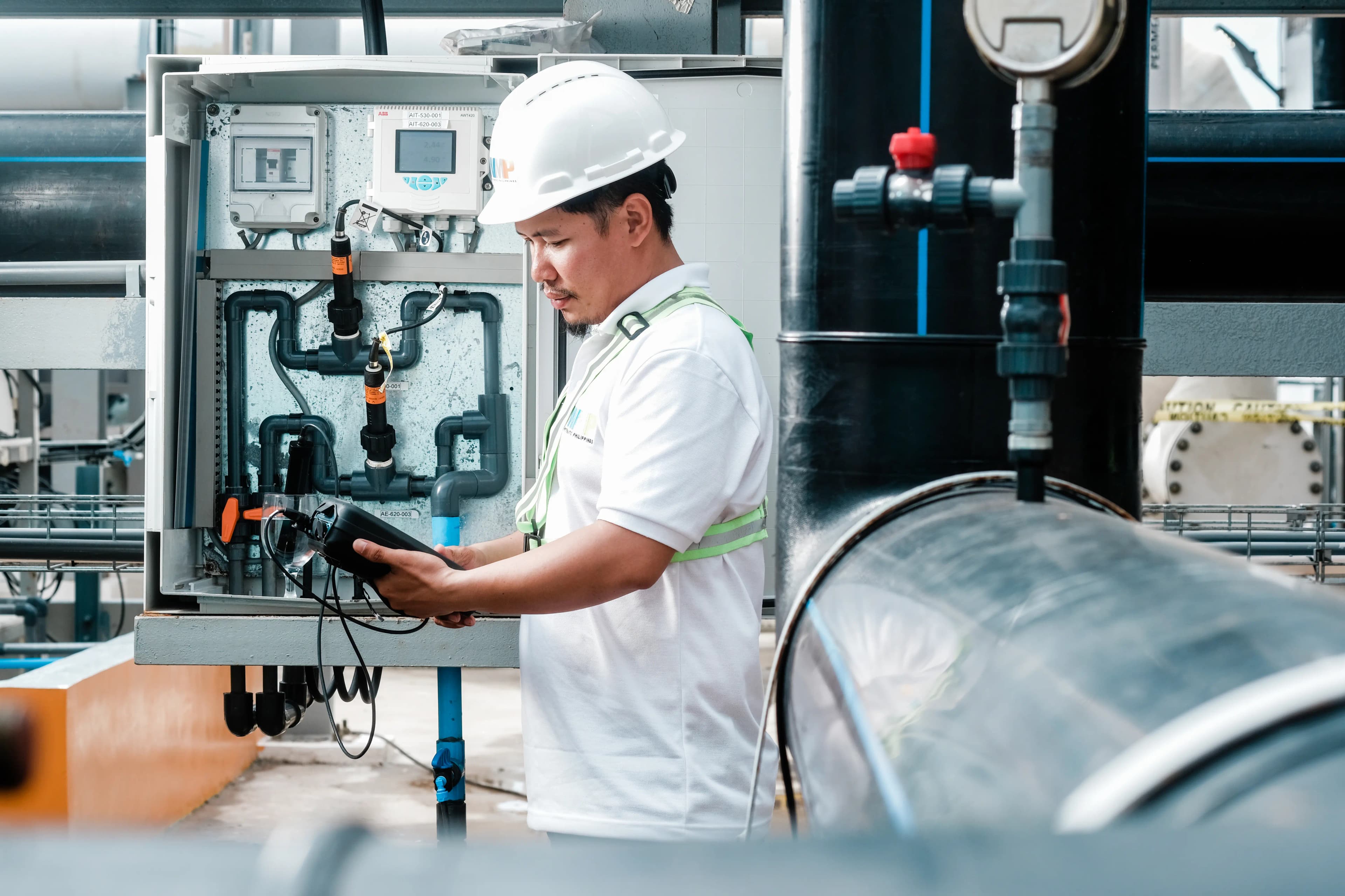 Worker standing around machinery with a device for measuring water quality.