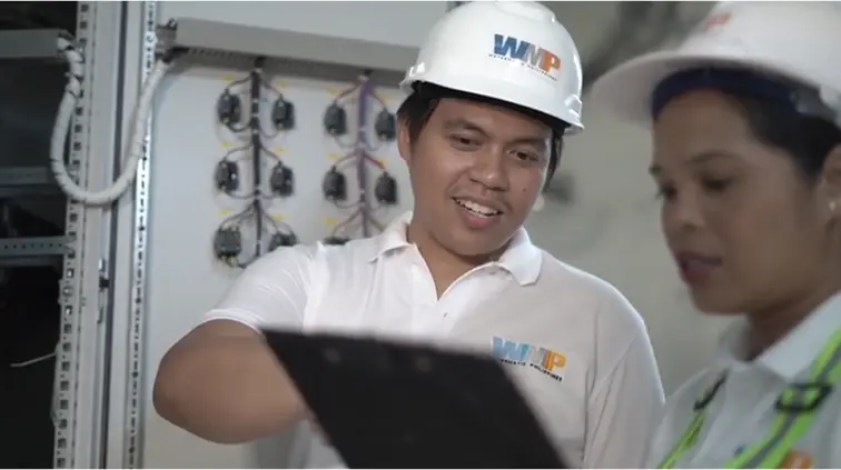 Worker showing another worker some data on a notepad.